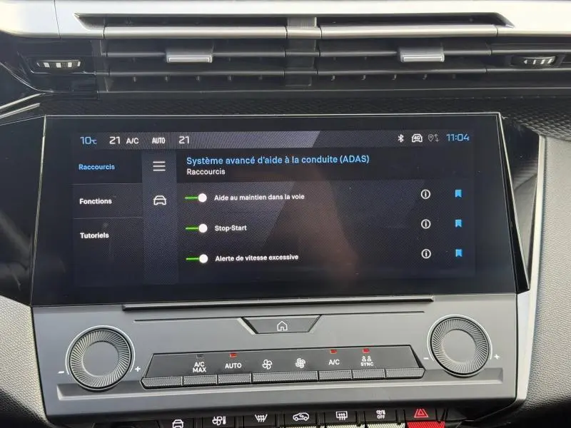 Écran tactile central du tableau de bord de la Peugeot 308 2024 blanc Okénite, affichant les aides à la conduite.