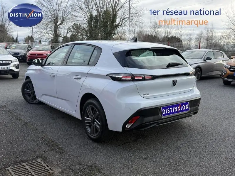 Peugeot 308 blanc Okénite vue 3/4 arrière droit, avec feux arrière distinctifs et logo Peugeot noir.