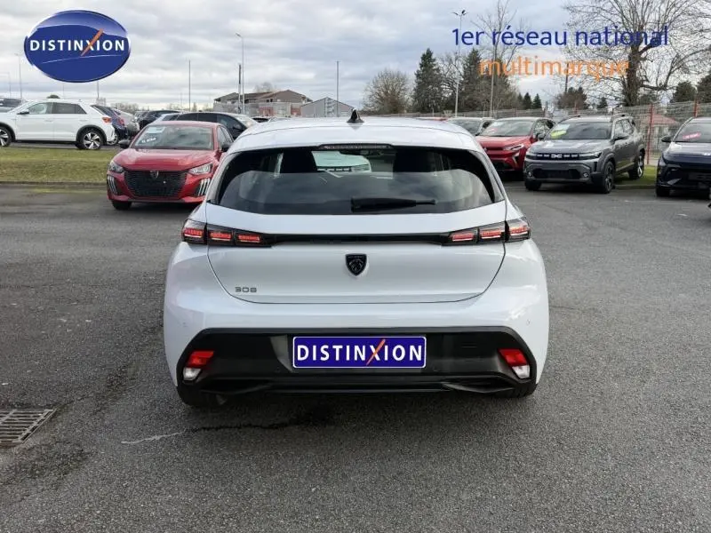 Vue arrière d'une Peugeot 308 blanche Okénite 2024, avec feux arrière LED distinctifs et logo central noir.