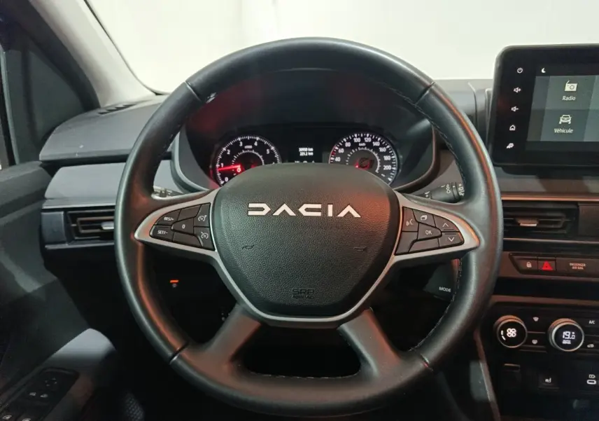 Vue rapprochée du volant cuir noir multifonctions de la Dacia Sandero 2024 avec tableau de bord et écran tactile.