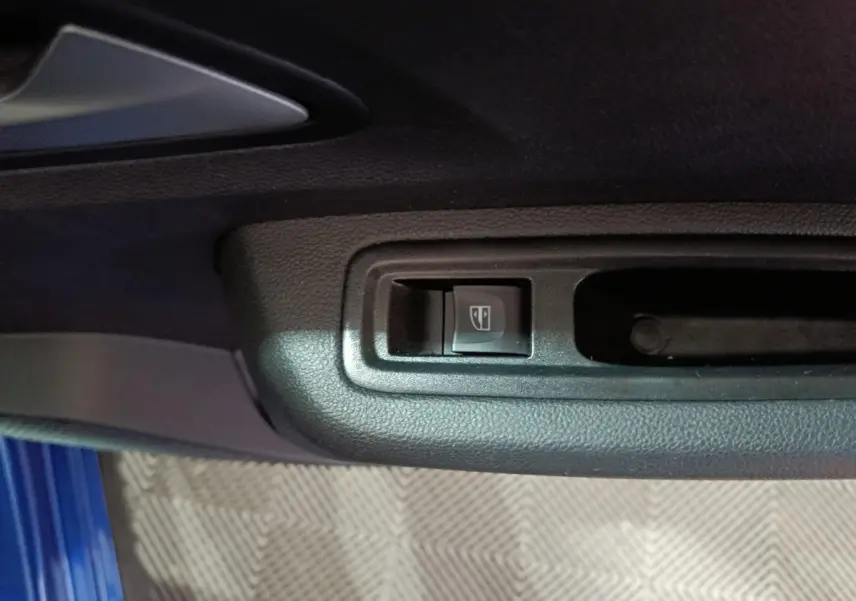 Gros plan sur le bouton de commande de la vitre électrique côté conducteur d'une Dacia Sandero bleu 2024.