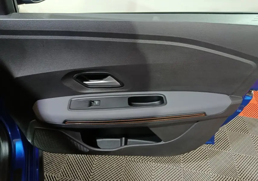 Vue rapprochée de la porte avant gauche bleu métallisé de la Dacia Sandero Extreme+ TCe 110 avec commande de vitre électrique.