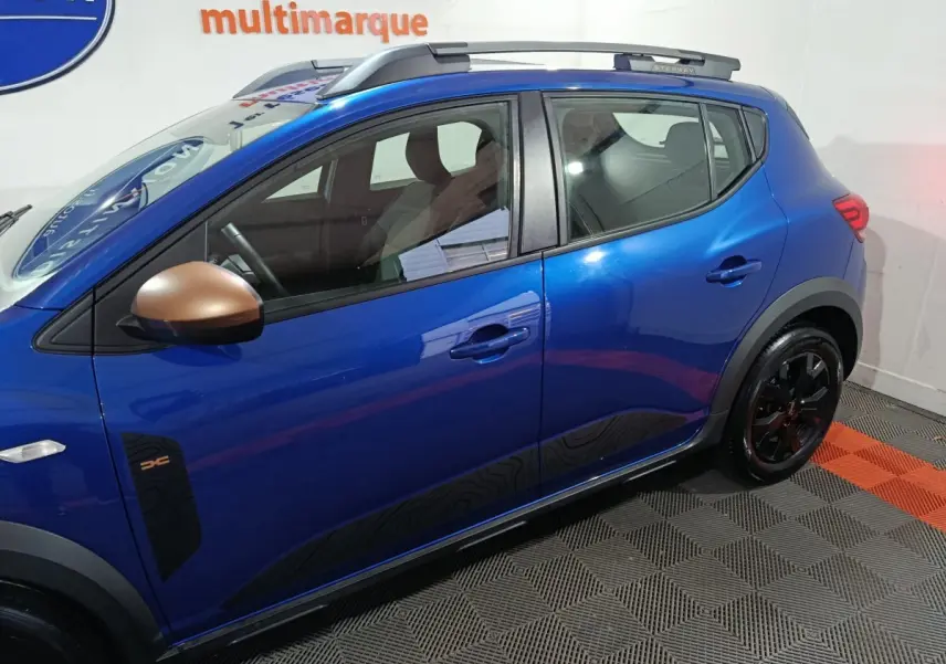Vue de profil côté gauche d'une Dacia Sandero Extreme+ bleu avec rétroviseur bronze et jantes noires.