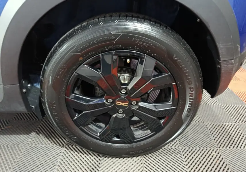 Gros plan sur la roue avant droite noire avec jante alliage du Dacia Sandero Extreme+ bleu 2024.