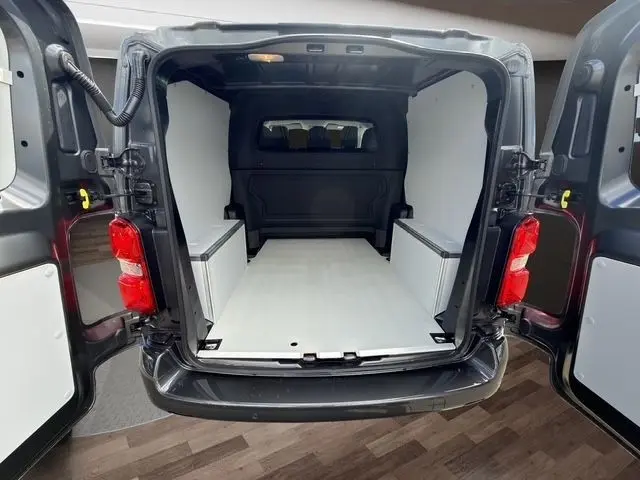 Vue arrière ouverte du Citroën Jumpy gris foncé, montrant l’espace de chargement aménagé avec kit bois blanc.