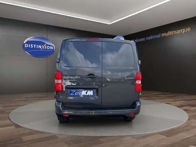 Vue arrière d’un Citroën Jumpy gris foncé, portes battantes fermées, dans un showroom avec logo Distinxion en arrière-plan.