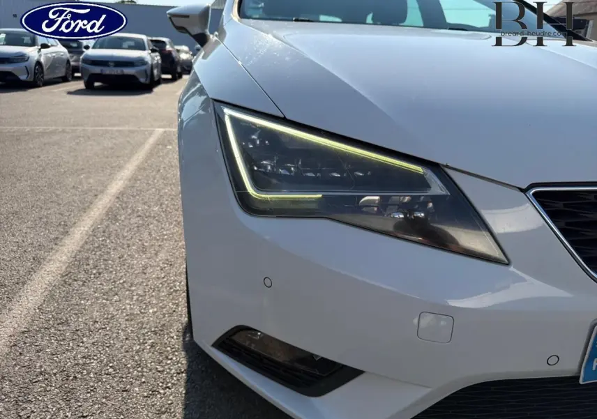 Gros plan sur l'avant droit gris étoile d'une SEAT Leon ST 2017, mettant en valeur le phare LED et la calandre.