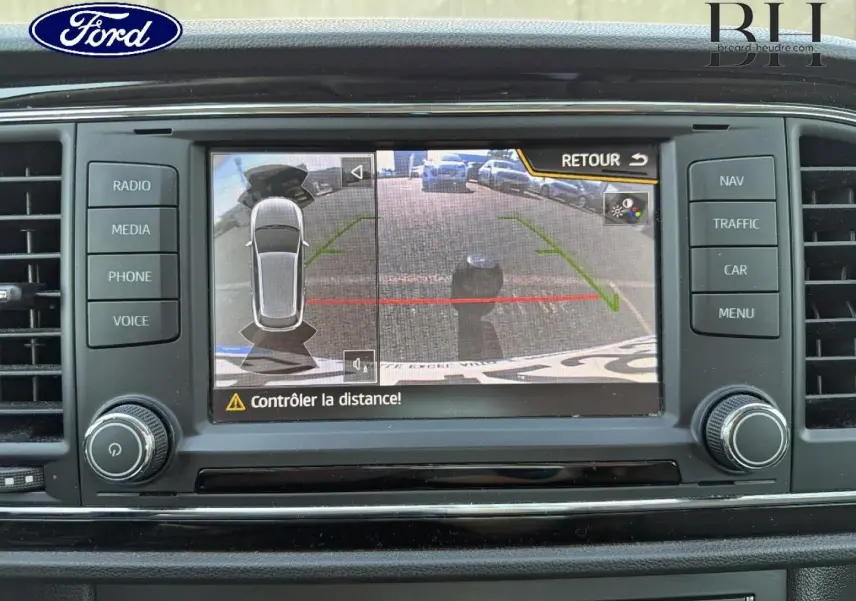 Écran tactile de système multimédia Ford montrant la caméra de recul avec alertes de distance, tableau de bord noir.