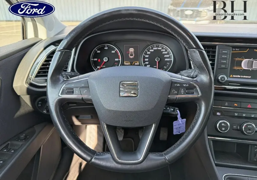 Vue intérieure centrée sur le volant cuir noir de la SEAT LEON ST avec tableau de bord et écran tactile visibles.