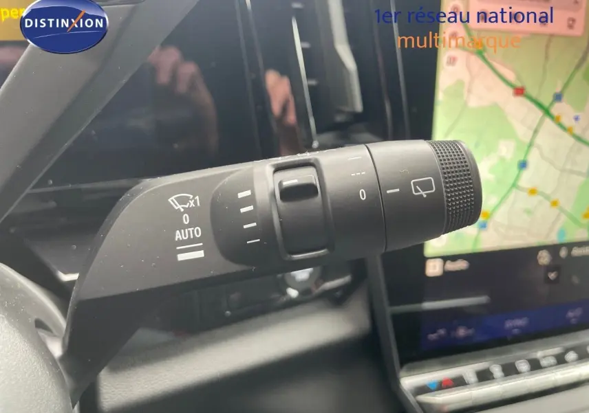 Gros plan sur la commande d'essuie-glace du Renault Austral gris schiste, avec écran tactile et navigation visible en arrière-plan.