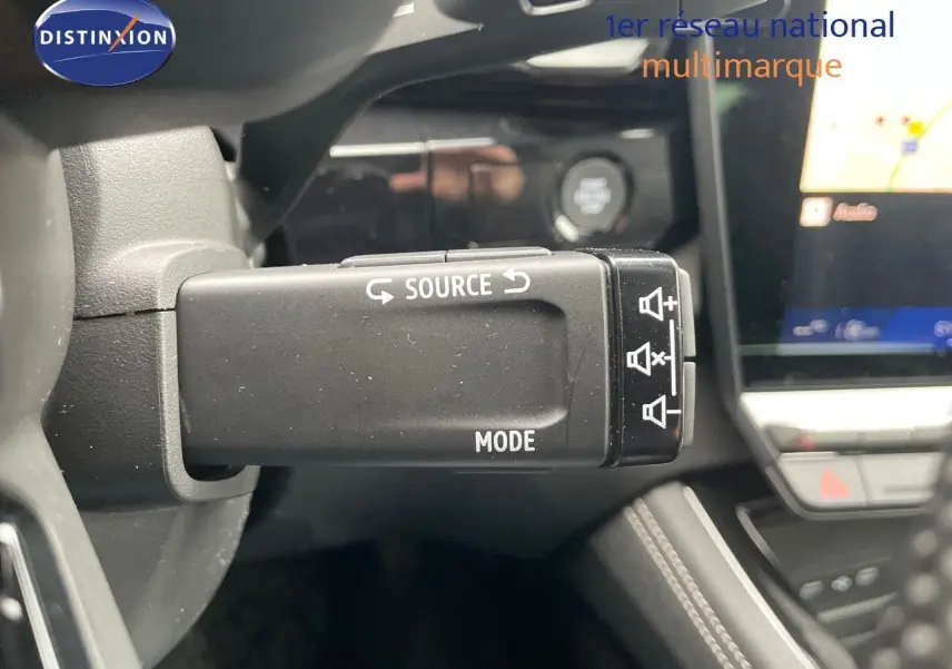 Gros plan sur la commande au volant du mode audio du Renault Austral E-Tech gris schiste, avec tableau de bord en arrière-plan.