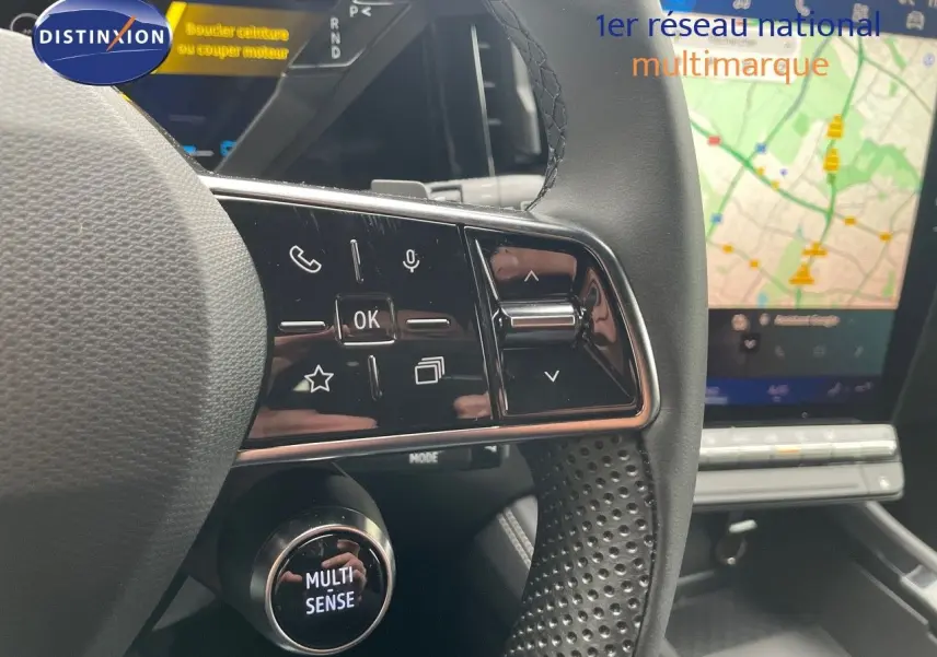 Gros plan sur le volant perforé et les commandes tactiles du Renault Austral gris schiste avec écran GPS en arrière-plan.