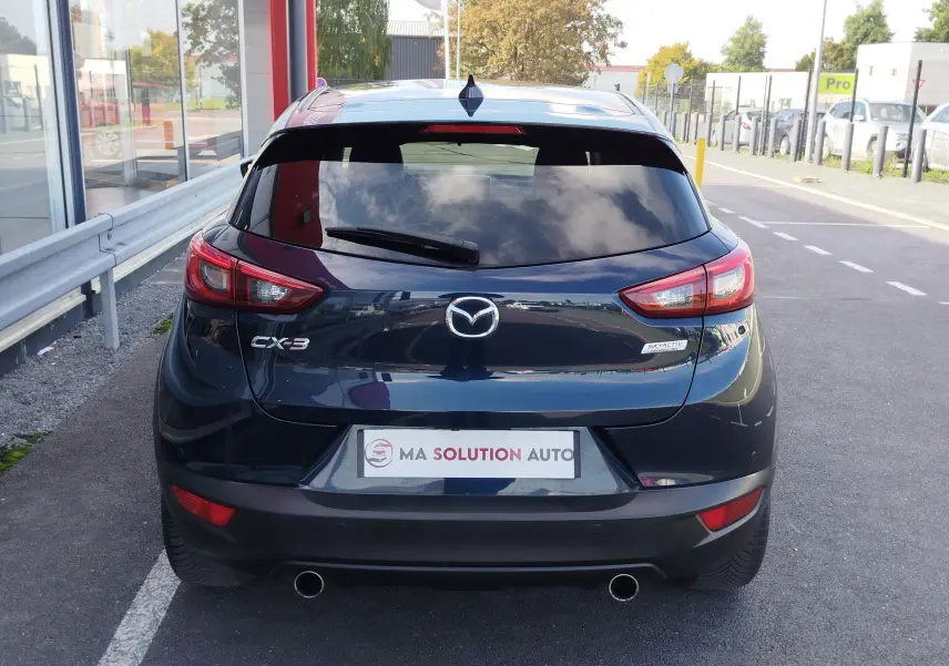 Vue arrière d'un Mazda CX-3 bleu Dynamic Mica 2016 avec feux LED et double sortie d'échappement visible.