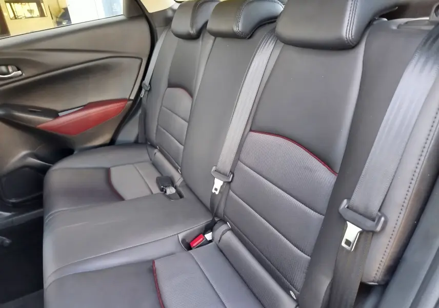 Vue latérale intérieure des sièges arrière en cuir noir avec surpiqûres rouges du Mazda CX-3 Dynamic Blue Mica 2016.