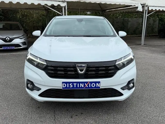 Vue de face d'une Dacia Sandero blanche glacier 2023 avec calandre noire et plaque Distinxion visible.
