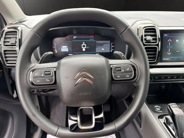 Vue rapprochée du volant cuir multifonctions noir du Citroën C5 Aircross 2022 avec tableau de bord numérique et écran tactile central.
