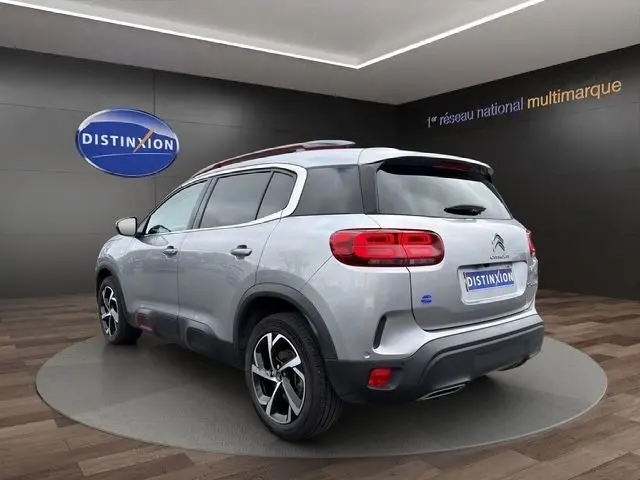 Vue 3/4 arrière droite d'un Citroën C5 Aircross gris clair avec toit noir et jantes alliage distinctives.