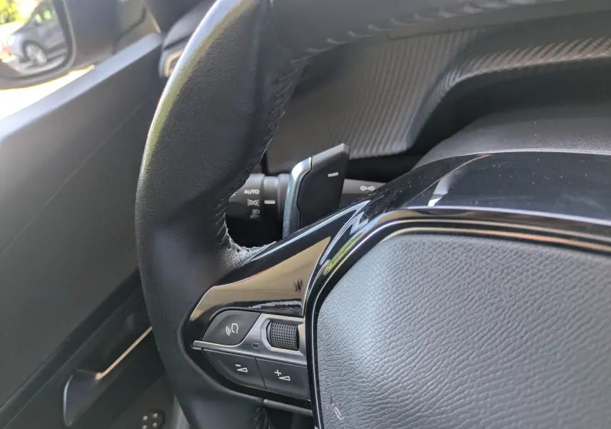 Gros plan sur la partie gauche du volant en cuir noir avec commandes intégrées du Peugeot 2008, intérieur moderne.