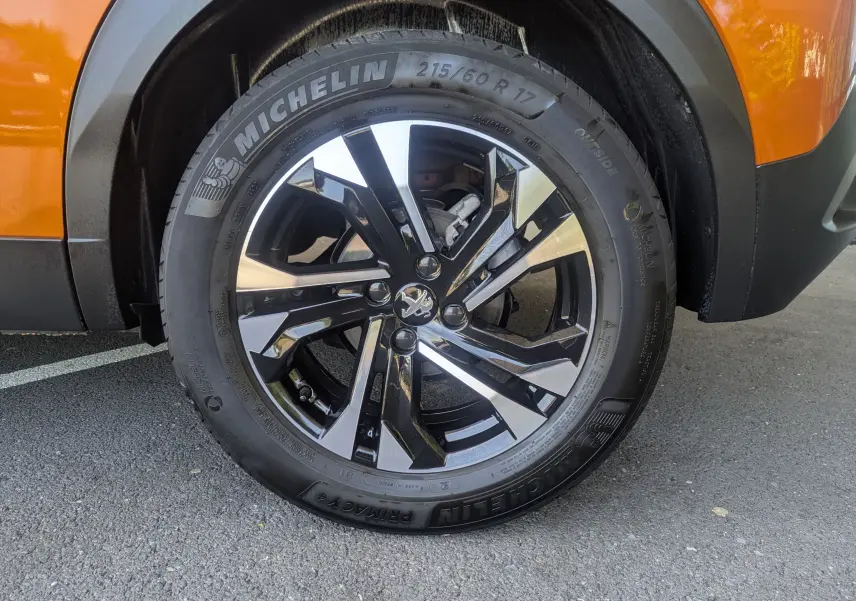 Gros plan sur la roue avant droite orange d’un Peugeot 2008 avec jante alliage noire et argent Michelin 17 pouces.
