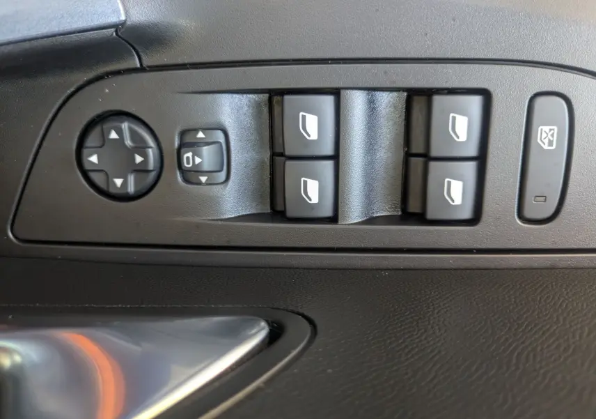 Gros plan sur les commandes de lève-vitres et réglages des rétroviseurs côté conducteur d’un Peugeot 2008 orange.