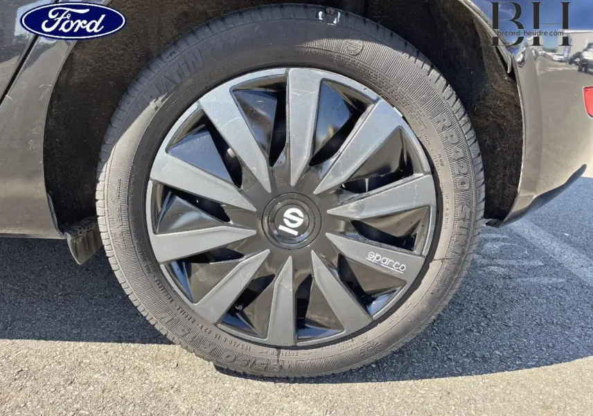 Gros plan sur la roue arrière droite noire Scala d'une Ford Fiesta 2015 avec enjoliveur Sparco gris et noir.
