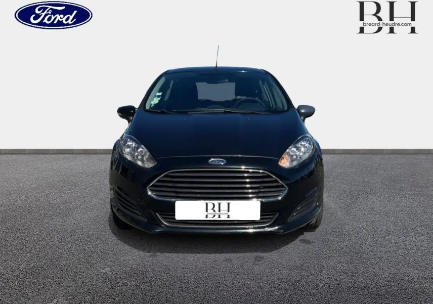 Vue avant d'une Ford Fiesta noire Scala de 2015 avec calandre chromée et phares allumés sur fond neutre.