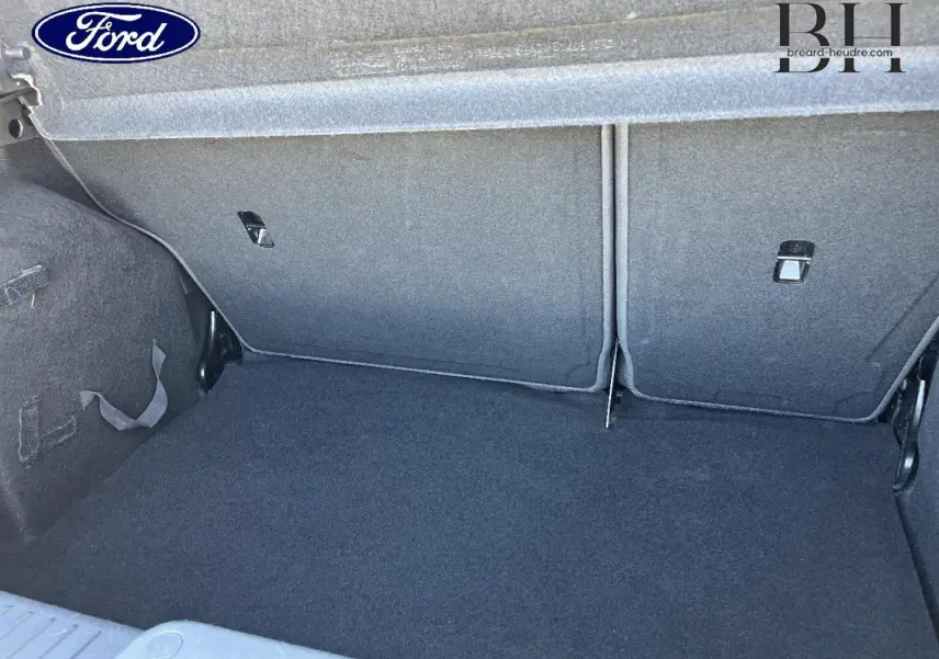 Coffre ouvert de la Ford Fiesta noir Scala, vue intérieure montrant la banquette arrière rabattable et le tapis de coffre.