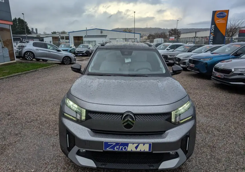Citroën C3 Aircross gris métallisé vue de face avec toit noir et phares LED allumés sous la pluie.