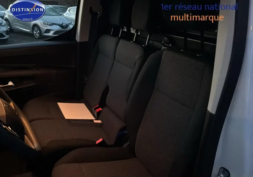 Vue intérieure côté conducteur du Citroën Berlingo Fourgon blanc, montrant les sièges avant et la cloison de séparation.