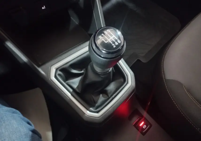 Gros plan sur le levier de vitesses manuel noir et la commande de frein à main électrique rouge dans l’habitacle d’une Dacia Sandero 2024.