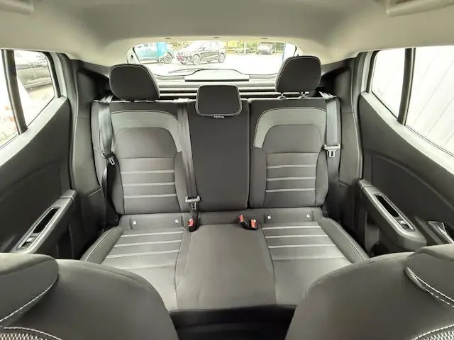 Vue intérieure arrière des sièges arrière gris foncé et clair du Dacia Sandero 2023, avec ceintures de sécurité visibles.