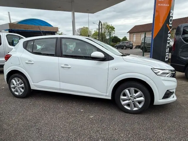 Vue de profil côté gauche d'une Dacia Sandero blanche glacier 2023, compacte avec jantes alliage et lignes épurées.