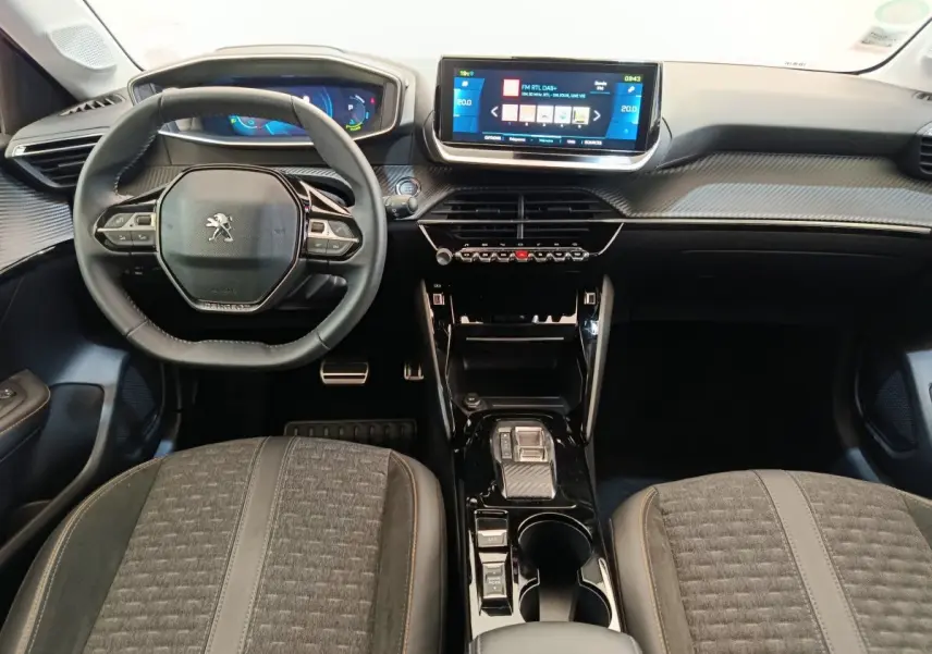 Vue intérieure frontale du tableau de bord et volant cuir de la Peugeot 208 Electrique Roadtrip 2022 avec écran tactile central.