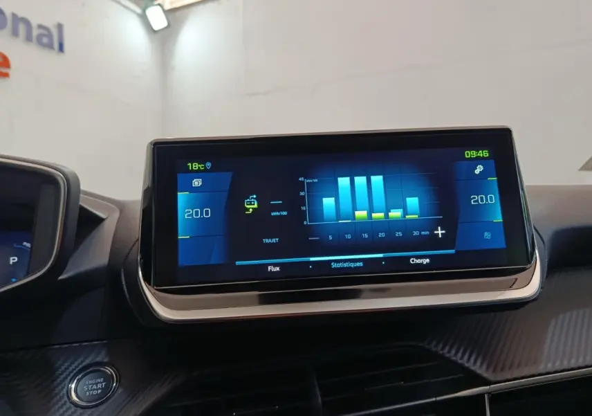 Écran tactile central affichant les statistiques de consommation sur le tableau de bord d'une Peugeot 208 électrique gris clair.