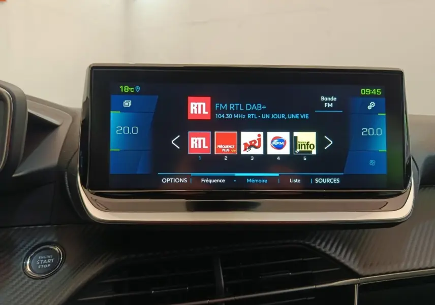 Écran tactile central de 10 pouces affichant la radio dans l'habitacle d'une Peugeot 208 électrique gris clair.