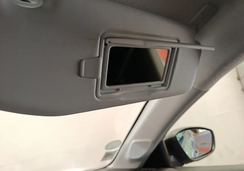 Détail du miroir de courtoisie sur pare-soleil côté conducteur dans l'habitacle gris clair d'une Peugeot 208 Electrique.