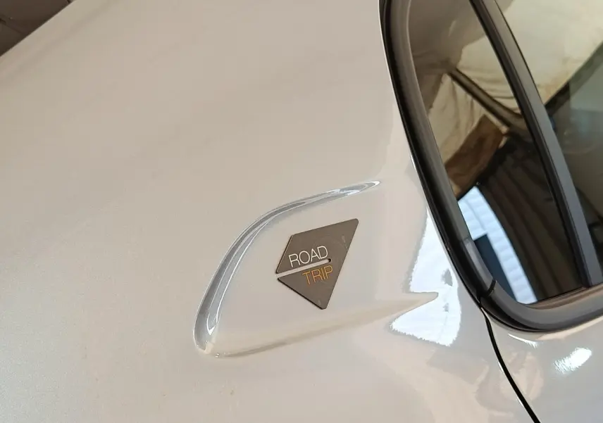 Détail du logo Roadtrip sur la porte arrière côté droit d’une Peugeot 208 électrique gris clair.
