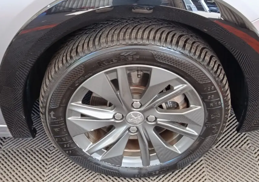 Gros plan sur la roue avant gauche gris clair d'une Peugeot 208 Electrique ROADTRIP 2022 avec jante alliage.