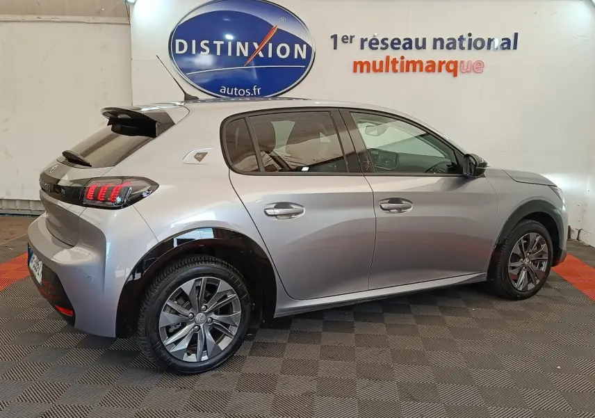 Peugeot 208 électrique gris clair vue de profil côté gauche, avec jantes alliage et feux arrière LED distinctifs.