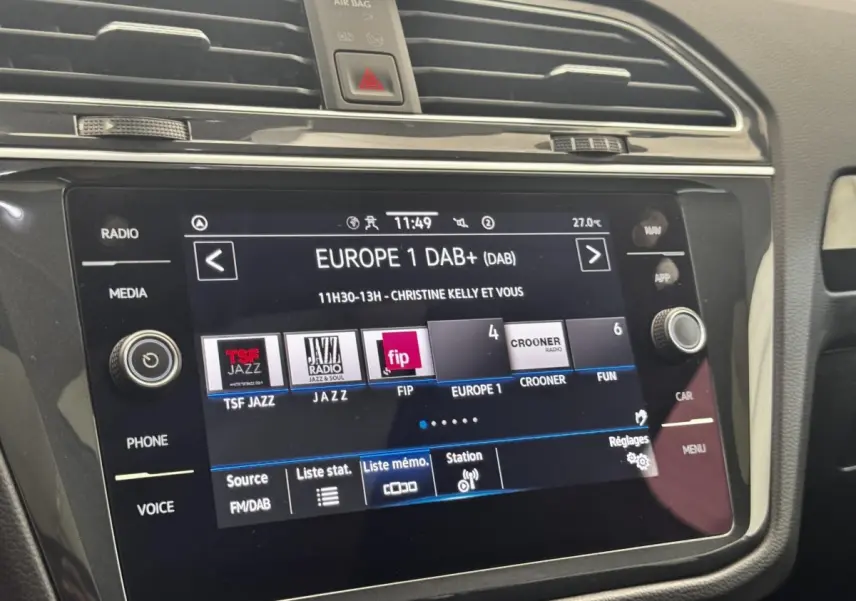 Gros plan sur l’écran tactile central du Volkswagen Tiguan 1.5 TSI gris clair affichant les stations radio DAB+ en intérieur.