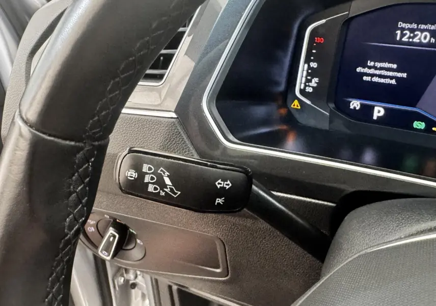 Gros plan sur le volant et le commodo gauche du tableau de bord du Volkswagen Tiguan 1.5 TSI gris clair, affichage numérique visible.