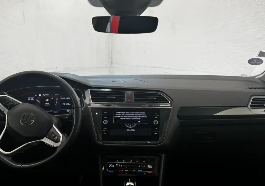 Vue frontale de l’habitacle du Volkswagen Tiguan 2021, tableau de bord noir avec écran tactile central et volant multifonctions.