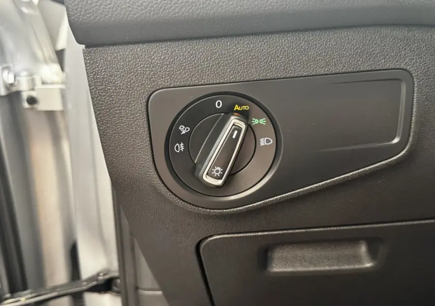 Gros plan sur le bouton de commande des phares à gauche du volant dans un Volkswagen Tiguan gris clair 2021.