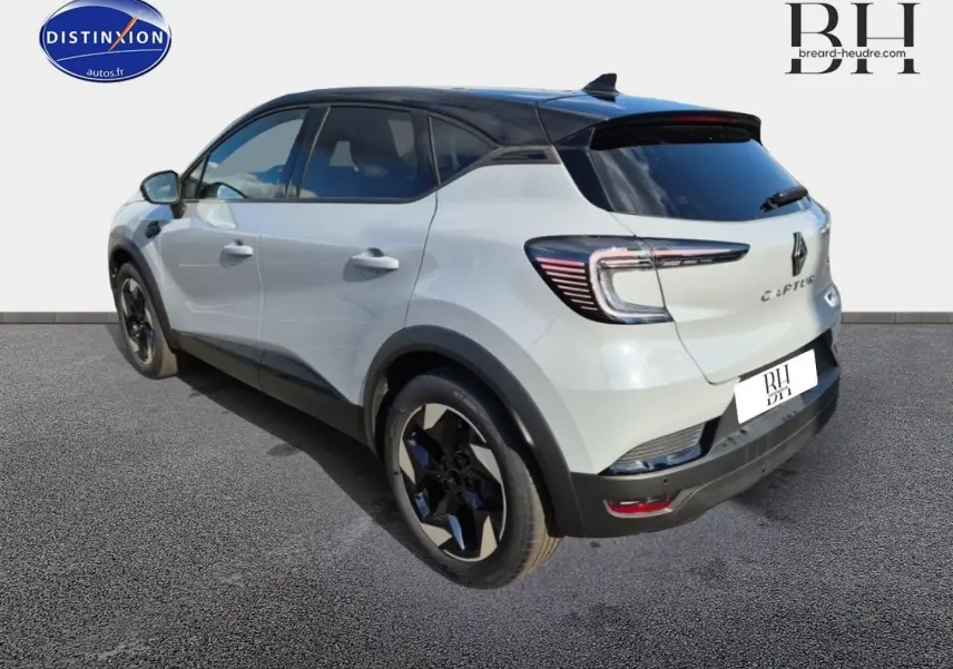 Vue 3/4 arrière gauche d'un Renault Captur 2025 blanc avec toit noir et jantes noires distinctives.