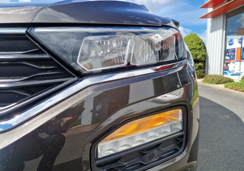 Gros plan sur le phare avant droit du Volkswagen T-Roc chêne noir, mettant en valeur les feux LED et clignotant orange.