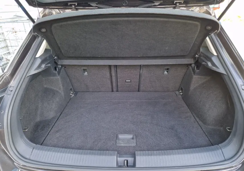 Coffre ouvert du Volkswagen T-Roc chêne noir, vue intérieure montrant l'espace de chargement et la moquette grise.