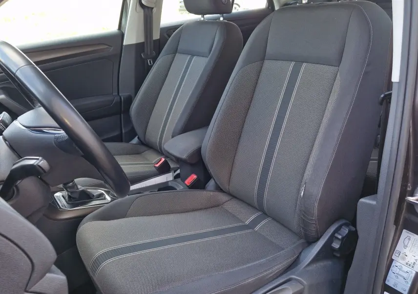 Vue intérieure côté conducteur du Volkswagen T-Roc chêne noir, mettant en valeur les sièges avant en tissu gris à rayures.