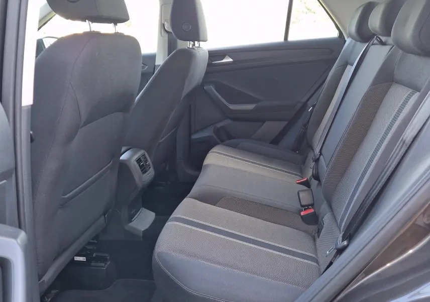 Vue intérieure côté droit arrière du Volkswagen T-Roc 2.0 TDi Lounge, sièges tissu gris avec détails rayés.