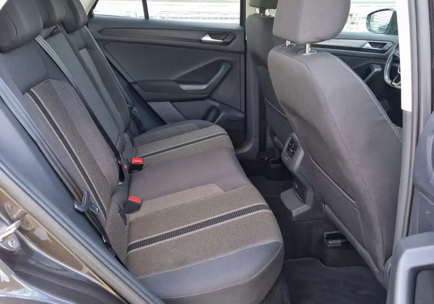 Vue intérieure côté gauche arrière du Volkswagen T-Roc chêne noir, montrant les sièges arrière en tissu et l'ouverture de porte.