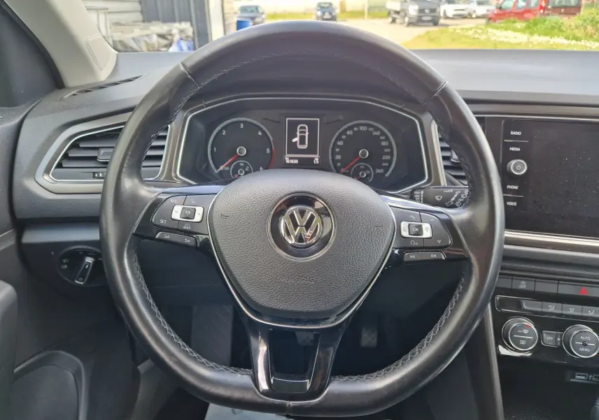 Volant en cuir noir de Volkswagen T-Roc 2.0 TDi 150 ch avec commandes intégrées et tableau de bord numérique visible.